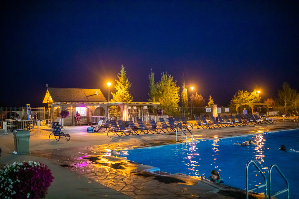 Outdoor pool at Fairmont Hot Springs Resort near Anaconda, Montana glowing at night with warm mineral water and pool deck chairs. Photo by Eric Bunting. 