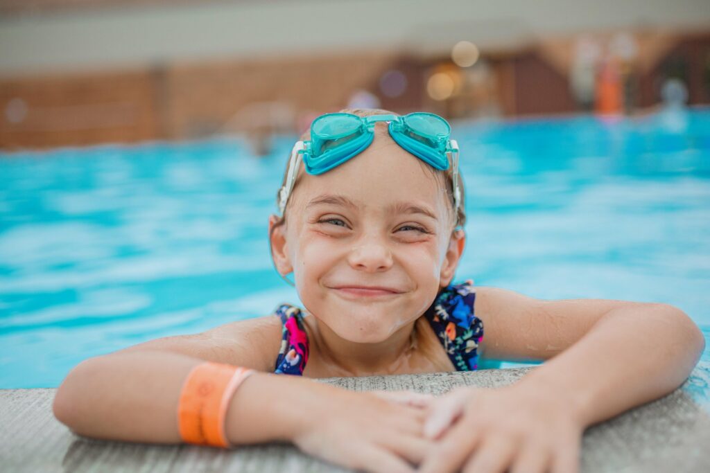 Young girl smiling at the pools edge at Fairmont Hot Springs Resort in Anaconda Montana. Experience a luxurious hot spring resort experience near Anaconda, Montana. Mineral rich waters, soothe, and relax, while the kids have fun in Southwest Montana!